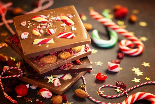 Some chocolate peppermint bark surrounded by candy, as part of candycore, one of the hottest 2023 holiday trends.