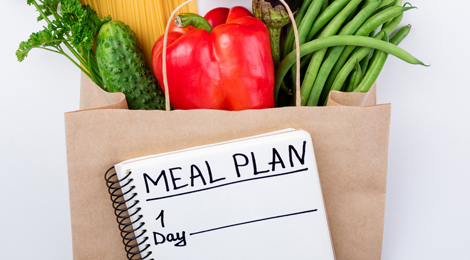 Meal planning list with bag of fresh, healthy groceries