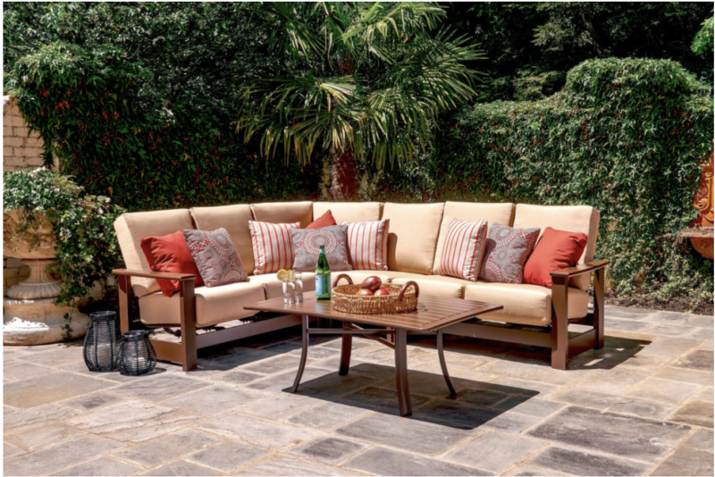 patio furniture sectional with orange pillows on stone patio