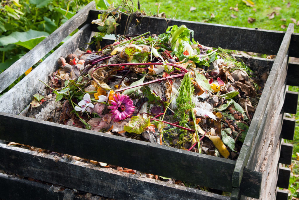 wooden compost bin in garden filled with compost materials