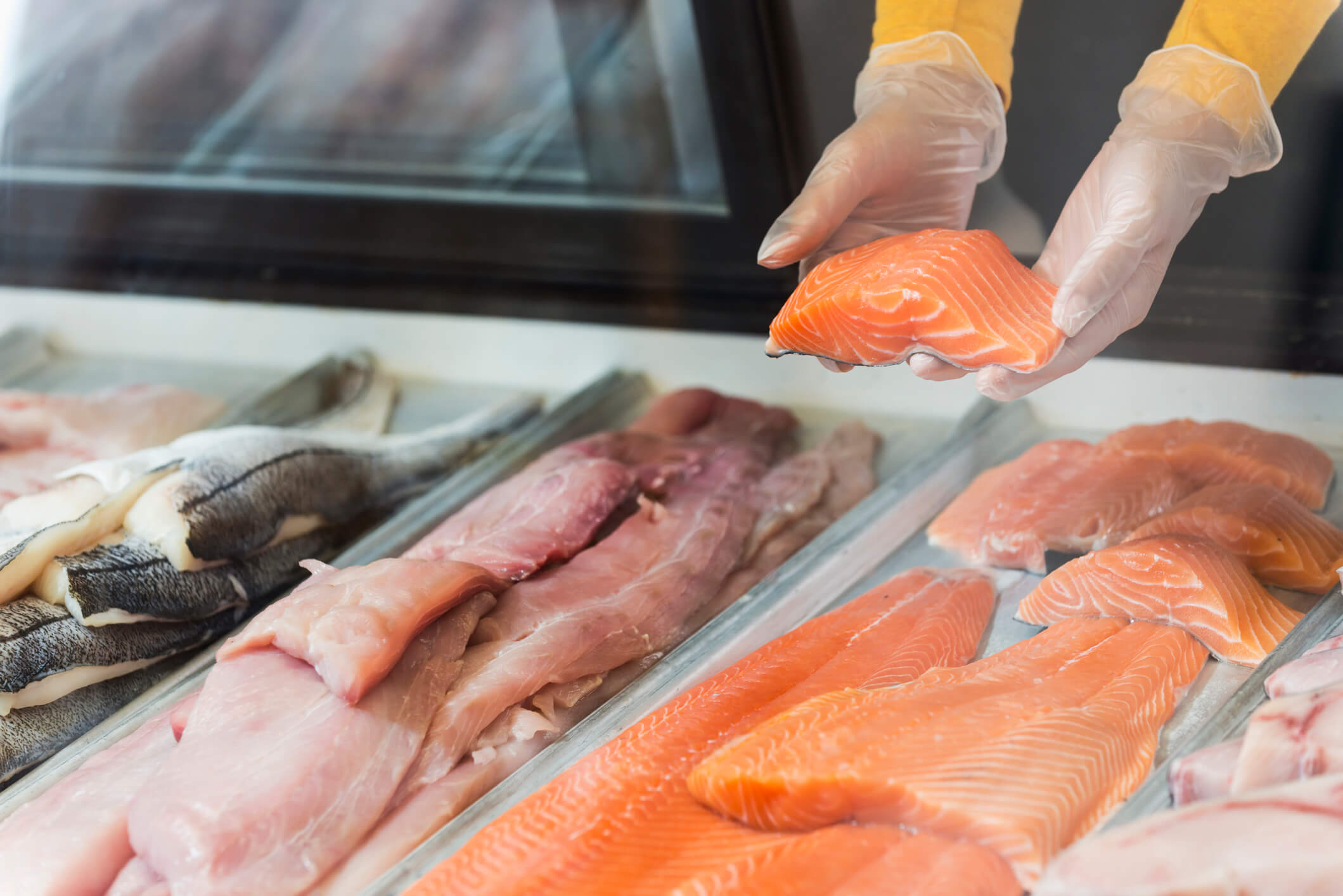 A grocer selects a fillet of fresh, local seafood.