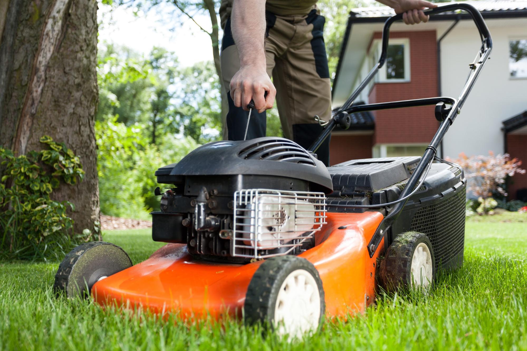 A person starts a mower to trim their lawn.