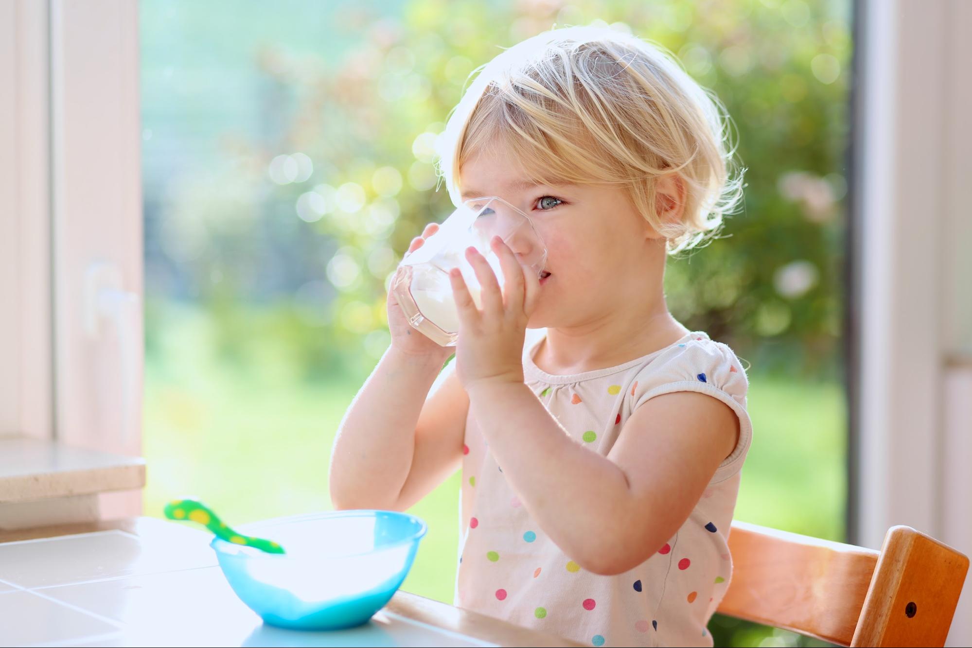 A young child enjoys a glass of milk.