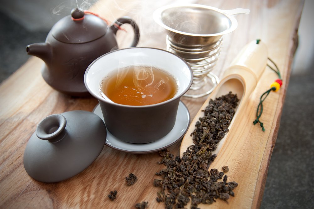 Oolong tea in a mug alongside a traditional kettle and steeping diffuser
