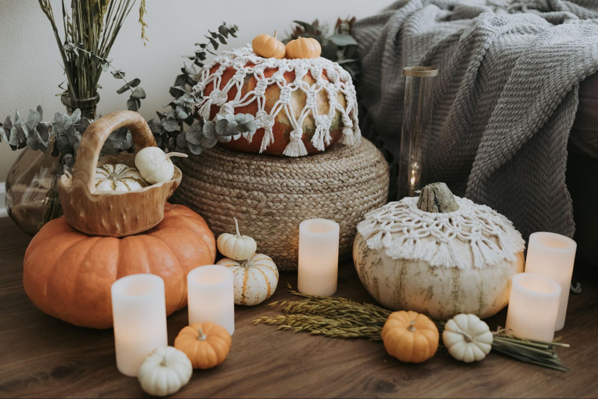 A beautiful fall display featuring candles, macrame, and pumpkins.