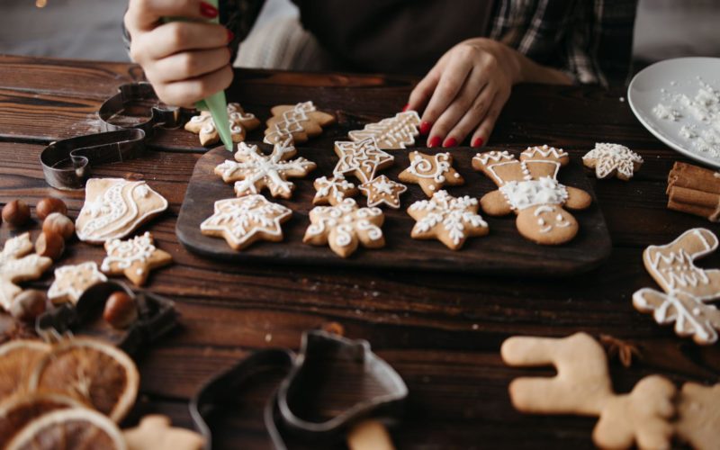 A person pipes icing onto gingerbread cookies for the holidays