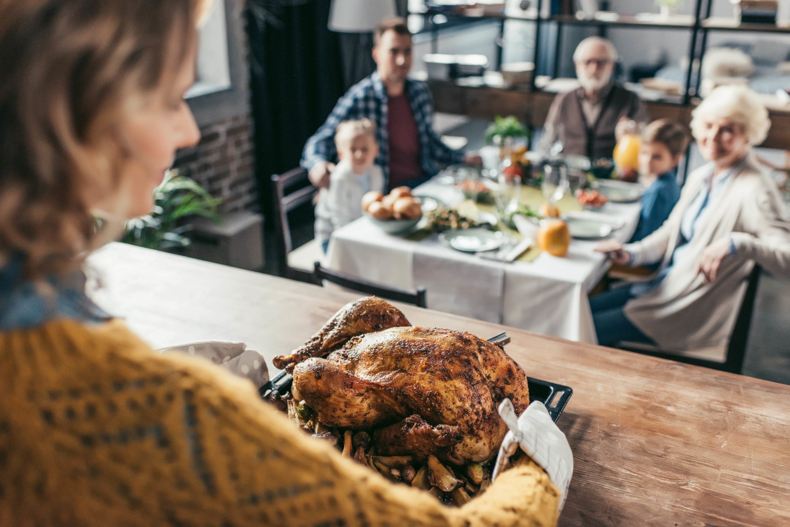 Woman presenting Thanksgiving turkey at dinner.