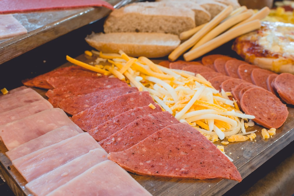 Closeup of sliced bologna and other meats and cheddar cheese