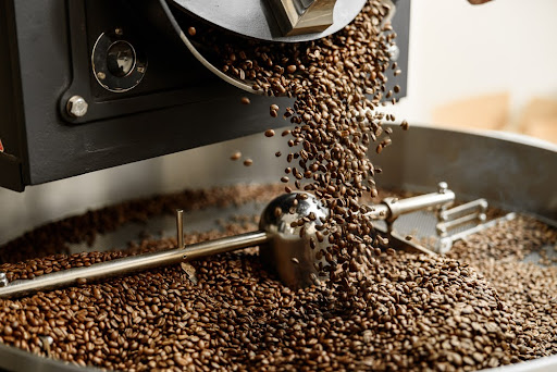 Coffee beans pour out of a roaster into a huge pile