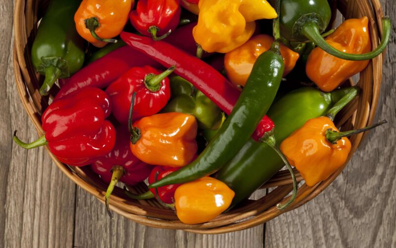 a basket of red, yellow, and green chili pepper varieties