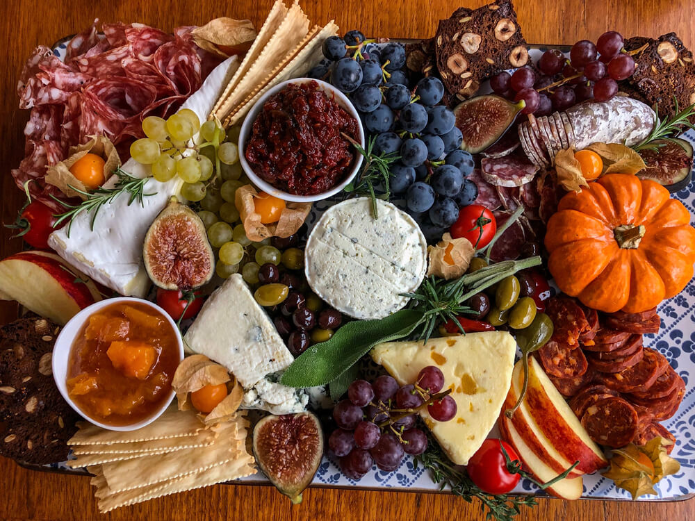 A charcuterie board filled with fruit, cheese, and jams for an easy Thanksgiving appetizer