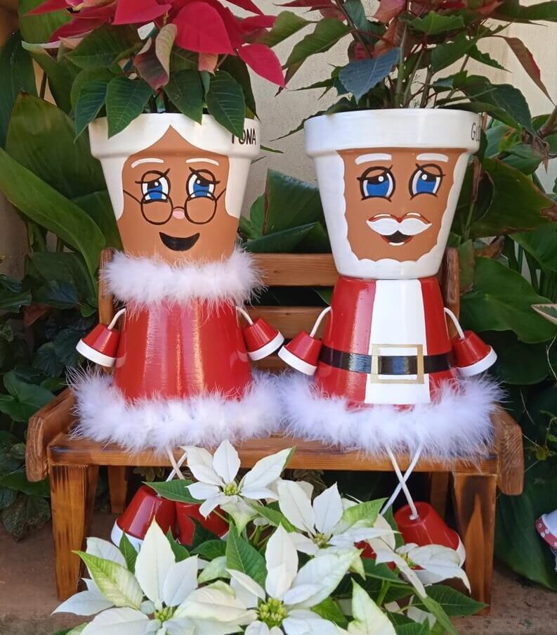 Poinsettias in pots painted like Santa Claus and Mrs. Claus