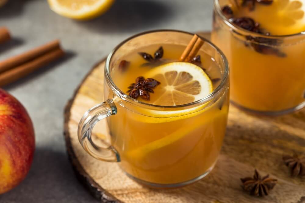 Apple cider mocktail in a clear mug with star anise and orange slices floating in it