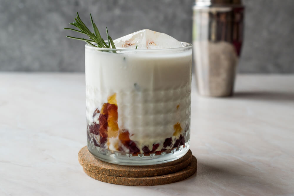 Christmas mocktail peppermitn white Russian drink in a clear class with a rosemary sprig.