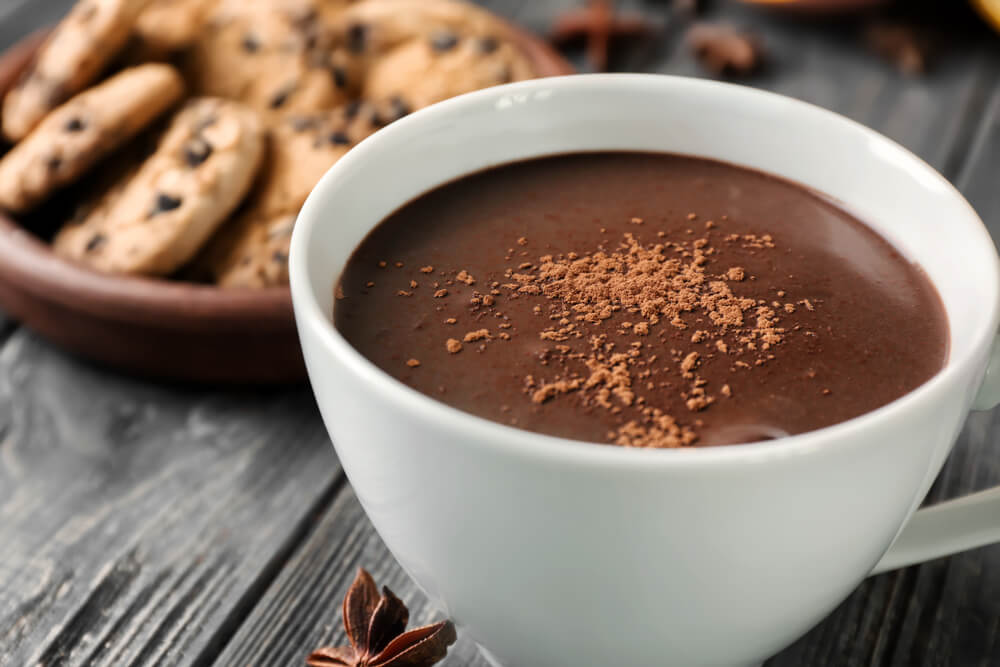 cookie butter gourmet hot chocolate recipe in a white cup with chocolate powder on top