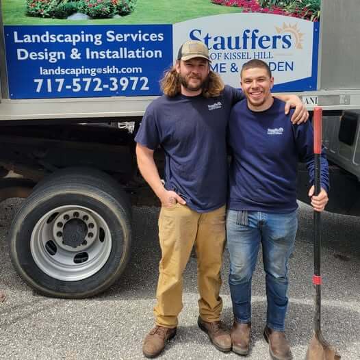 Two mulch installation workers put there arms around each other and smile