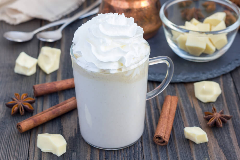 A cup of white coconut hot chocolate with whipped cream