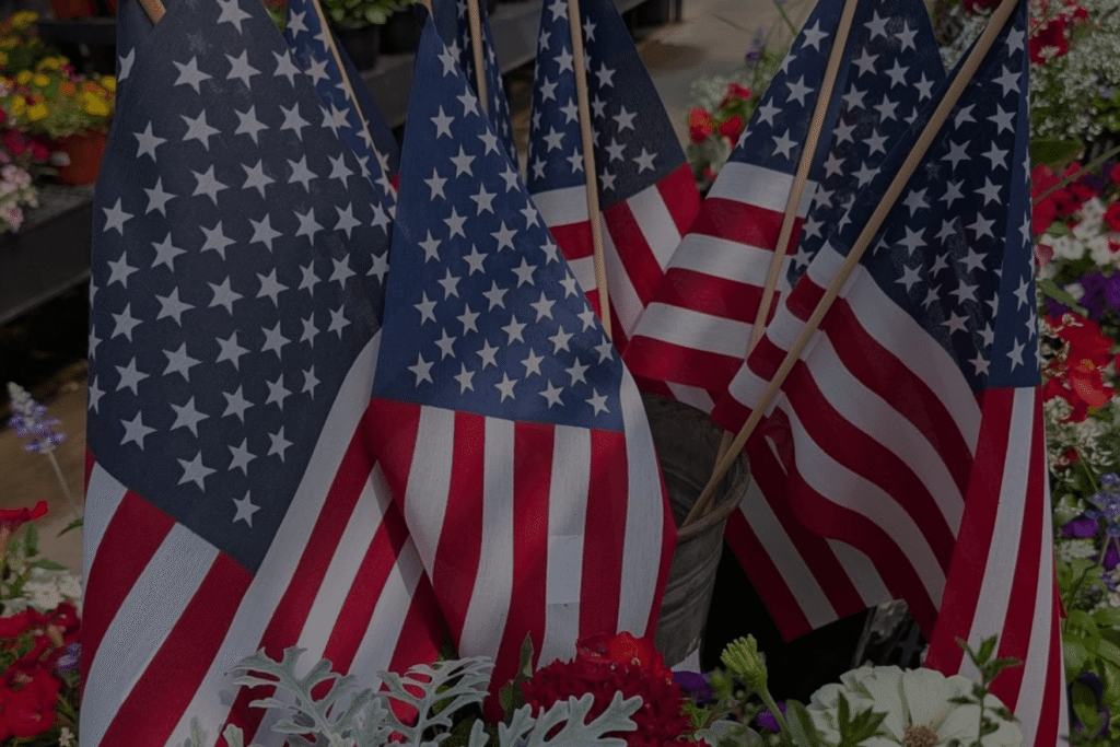 American flags in a bucket, surrounding by hanging flower baskets